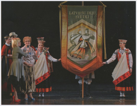 Marga Apsīte ar Latviešu deju svētku karogu savā 70 gadu jubilejas koncertā