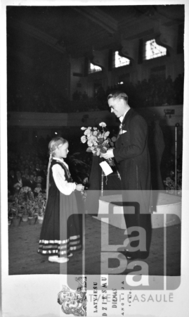 Diriģentu Daumantu Vītolu sveic pēc kora koncerta Anglijas latviešu Dziesmu dienās